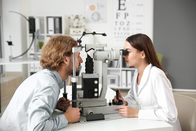 An optometrist examining a male patient’s eyes using a slit-lamp microscope in a clinic.