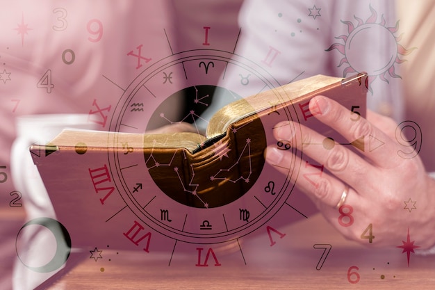 Hands holding an open book with zodiac symbols, constellations, and astrological signs overlaid in a mystical background.