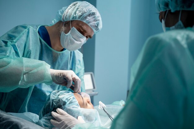 Surgeon performing eye surgery on a patient in an operating room with sterile equipment.
