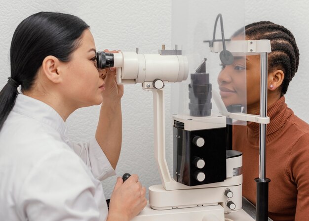 An eye doctor is performing a detailed slit lamp eye examination on a patient to check eye health and vision clarity in a clinic.