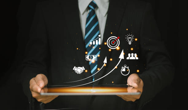 Business professional holding a tablet with digital growth icons like target, analytics, and strategy glowing on screen.
